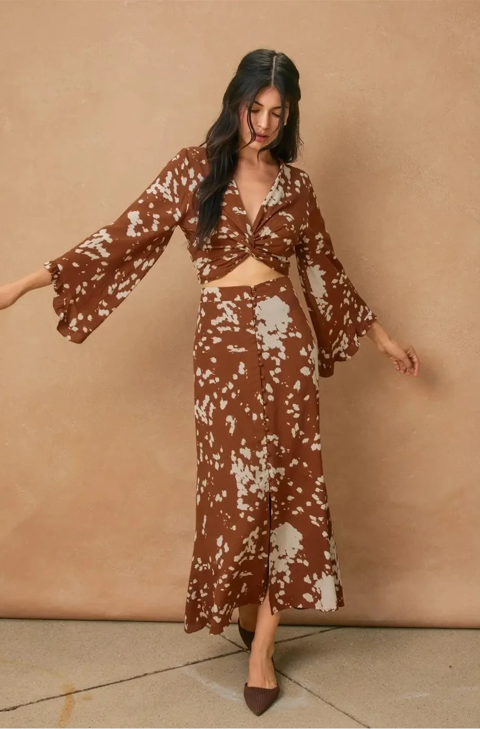 Woman wearing a brown and white patterned outfit against a beige background