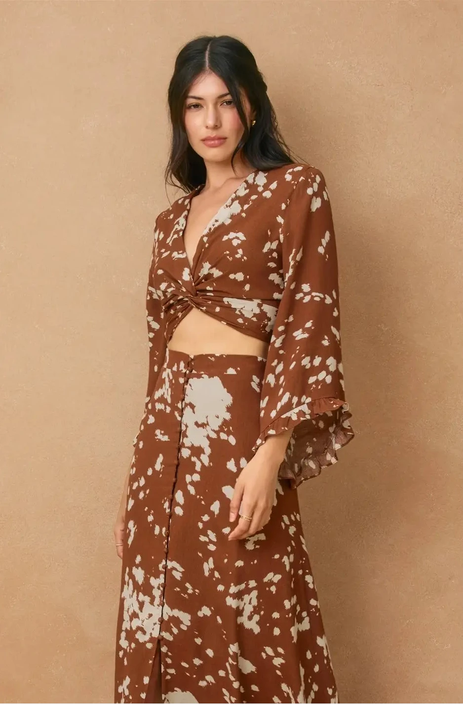 Woman wearing a brown floral outfit against a beige background