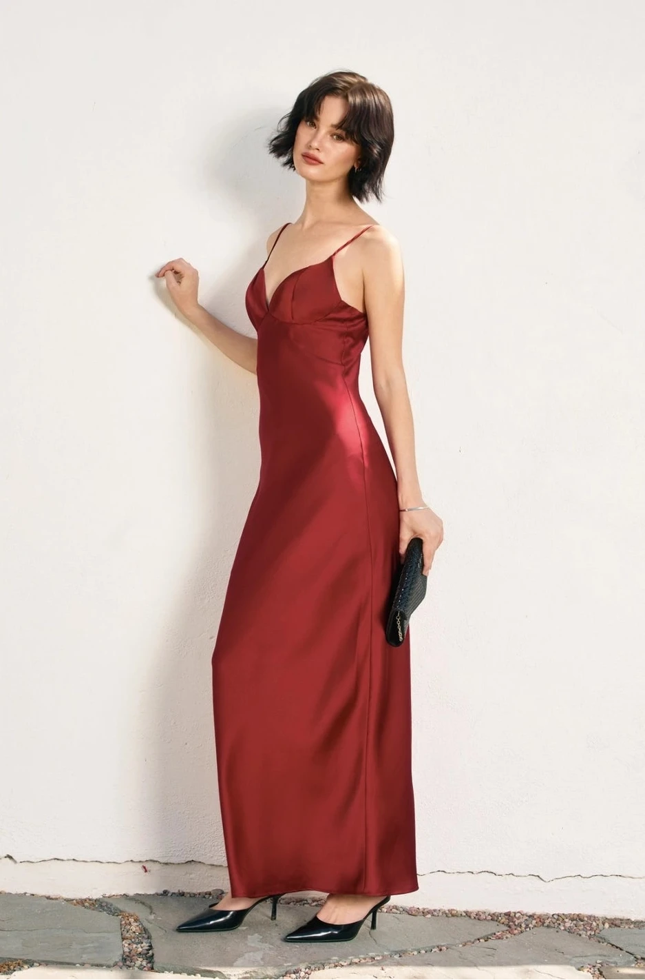 Woman in a red evening gown against a white wall